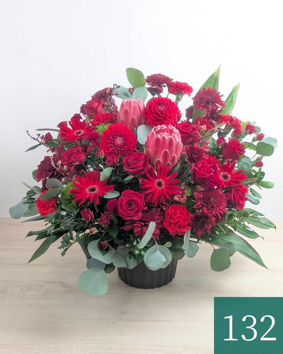 赤色の花、アレンジメント。ビジネスのお祝いに贈るフラワーギフト。