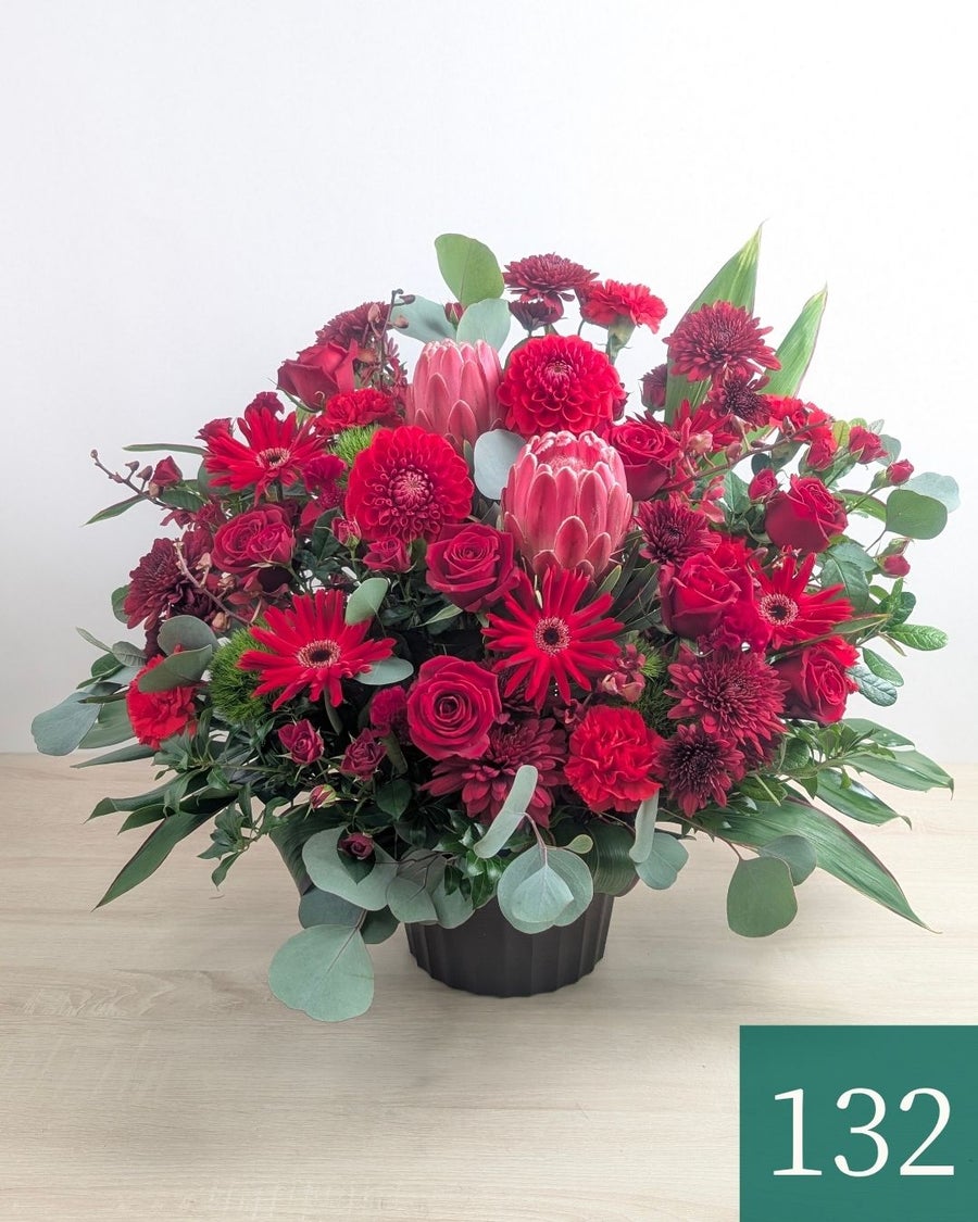 赤色の花、アレンジメント。ビジネスのお祝いに贈るフラワーギフト。