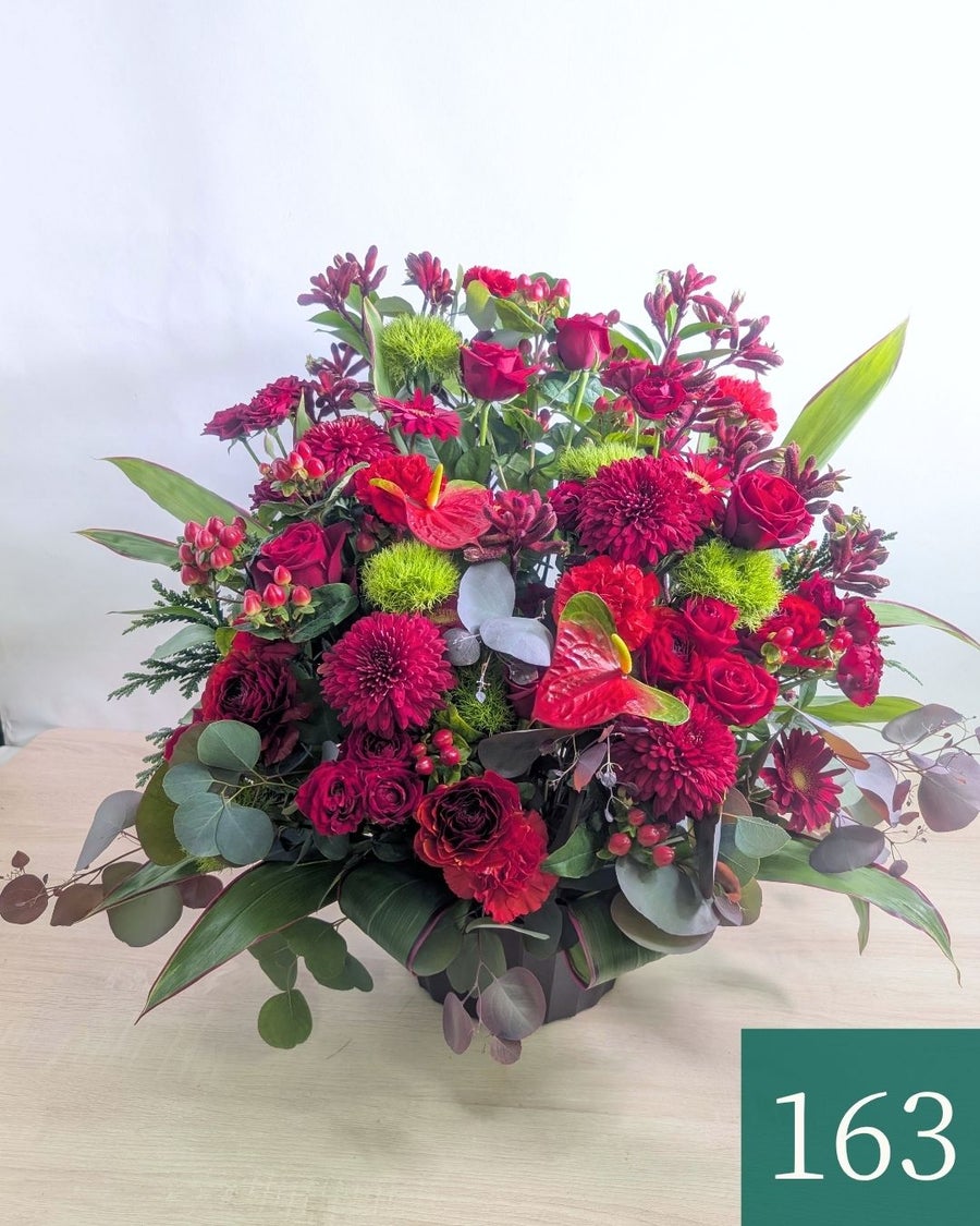 赤色の花、アレンジメント。ビジネスのお祝いに贈るフラワーギフト。