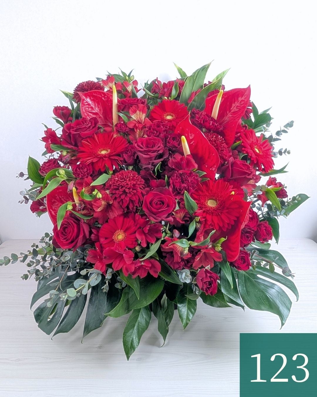 赤色の花、アレンジメント。ビジネスのお祝いに贈るフラワーギフト。